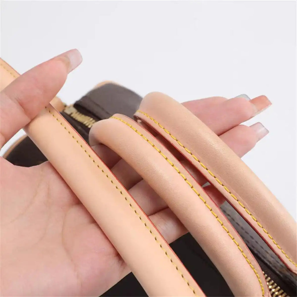 Soft beige leather bag strap with yellow stitching, held in hand for replacement or upgrade.